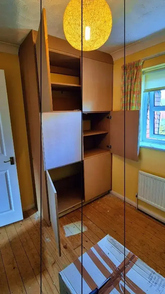 Fitted oak-effect bedroom wardrobes around a window with a desk section