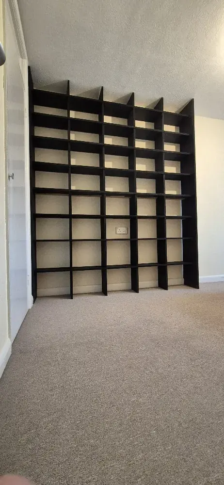Tall black built-in shelving unit covering a wall