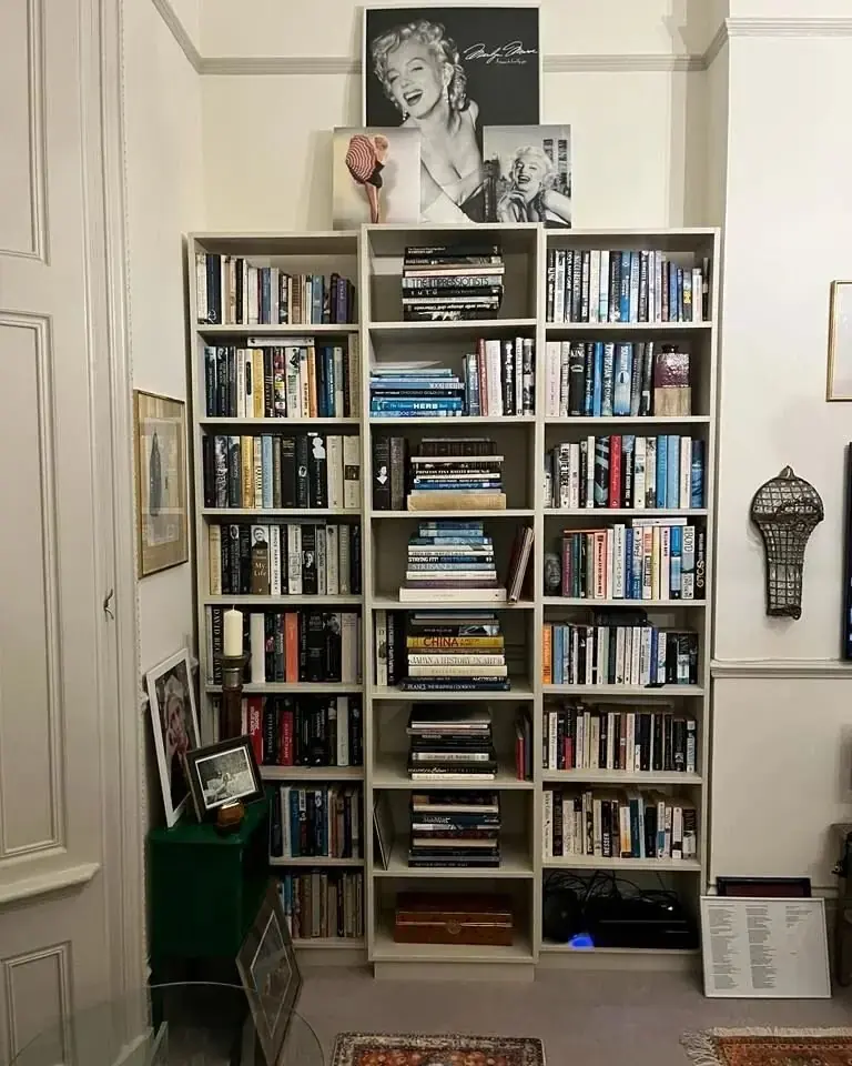Cream painted bookcase packed with books, built into a room corner up to the ceiling