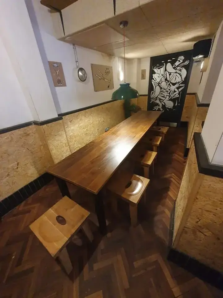 Long dark timber dining table and benches in a kitchen with patterned wallpaper