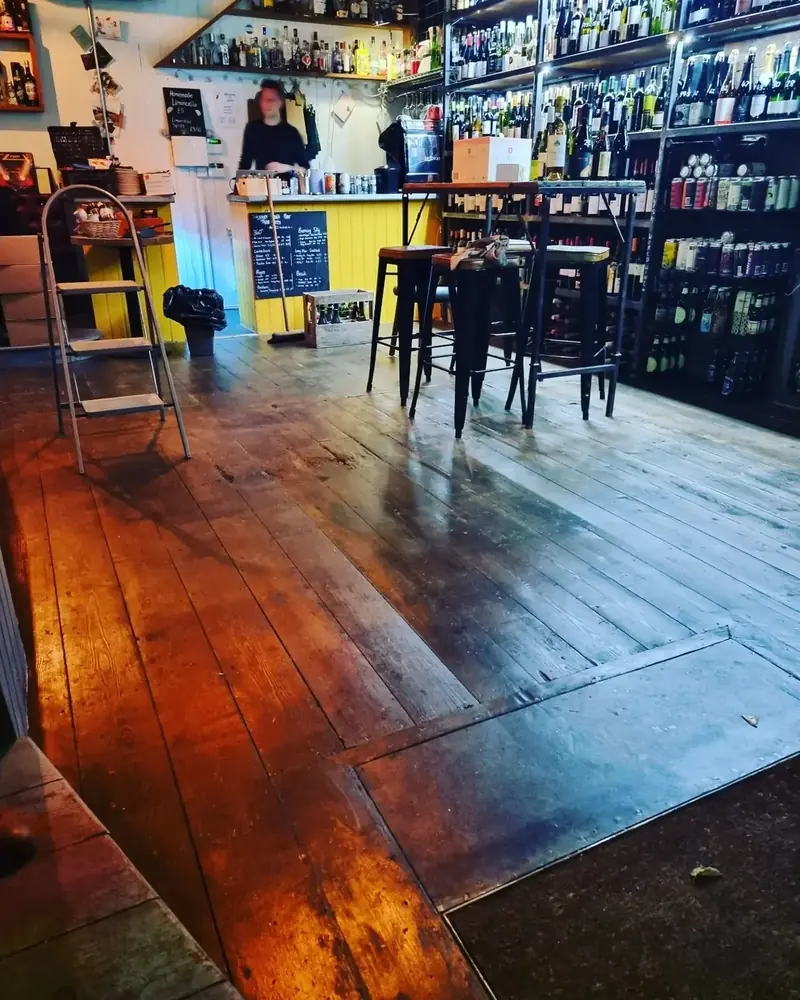 Bar interior with rich timber floorboards and bottle shelving
