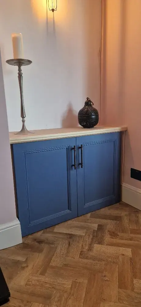 Blue painted cupboard standing on a herringbone parquet floor