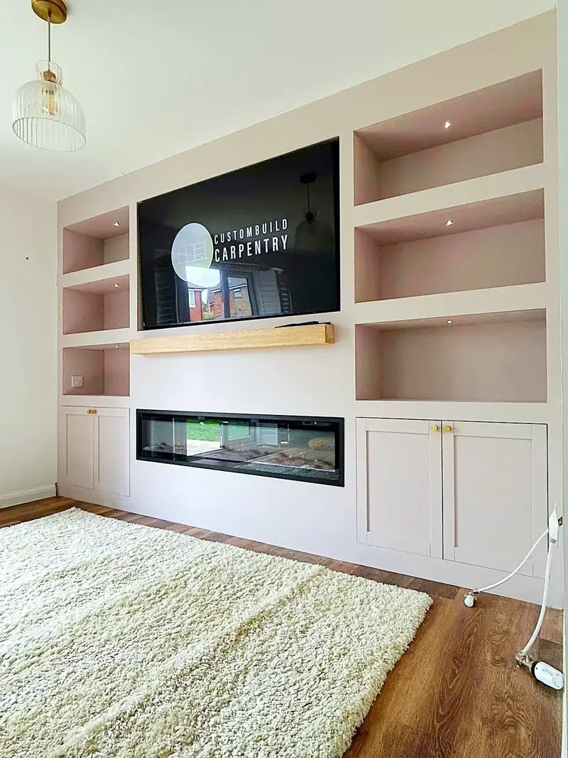 Cream media wall with open shelves, a TV recess, an oak shelf and a letterbox electric fire above cupboards