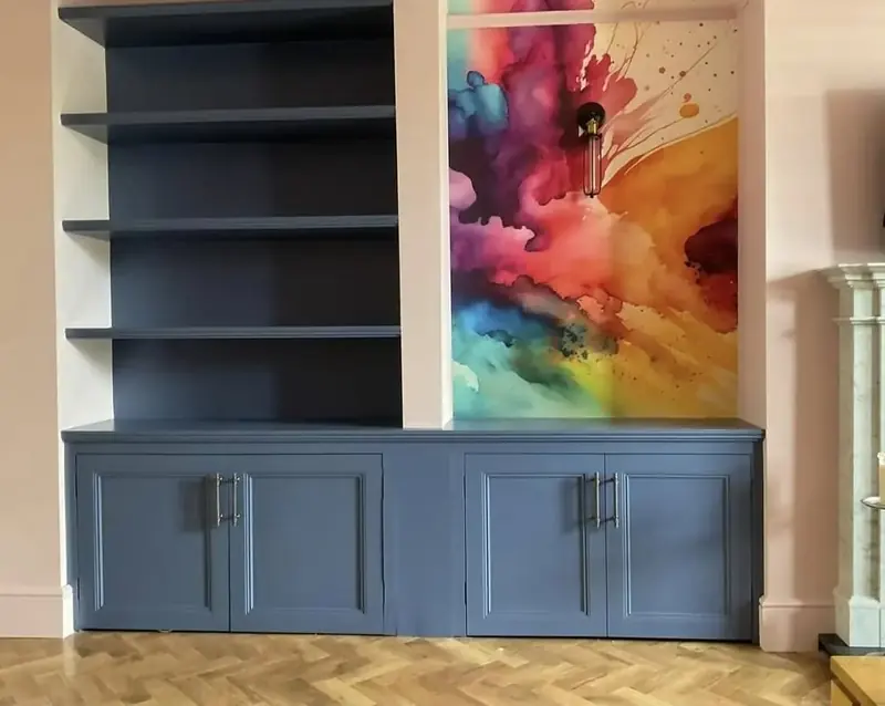 Dark navy built-in cupboards with shelves above, either side of a chimney breast with abstract artwork