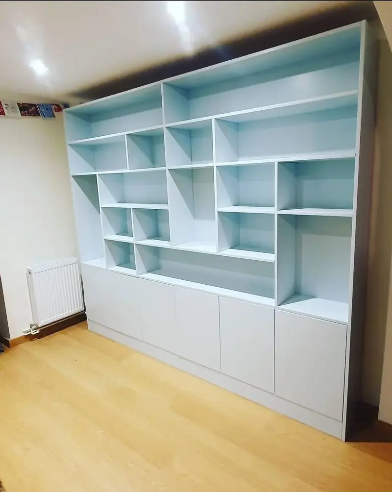 Wall-width built-in unit with staggered open shelves above low cupboards, painted pale blue