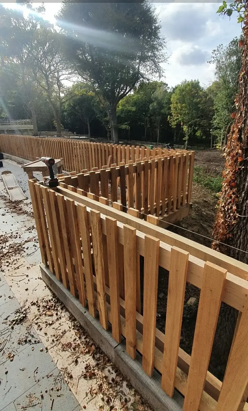 New timber picket fence following a slope beside trees