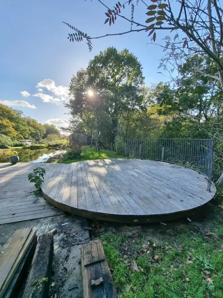 Large circular timber deck in a garden in low evening sun
