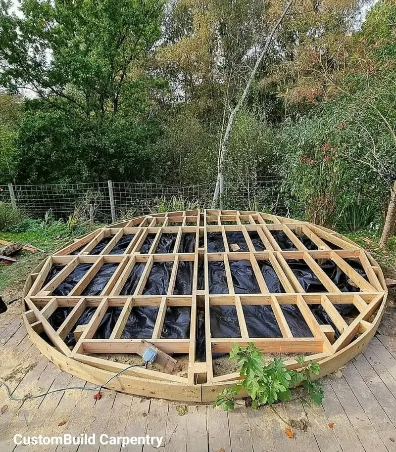 Timber subframe for a round deck laid out on a garden