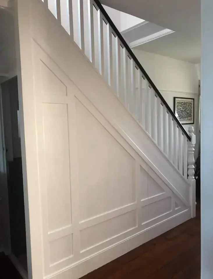 White panelled wall under a staircase with flush cupboard doors