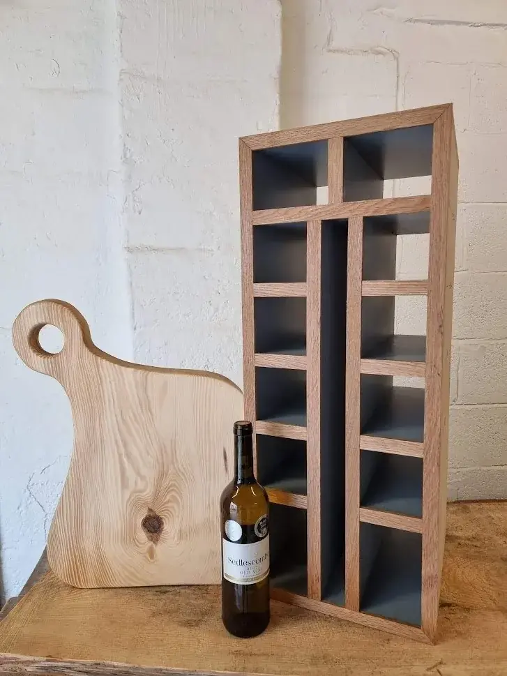 Small oak and grey wine rack beside a pine serving board and a bottle of wine